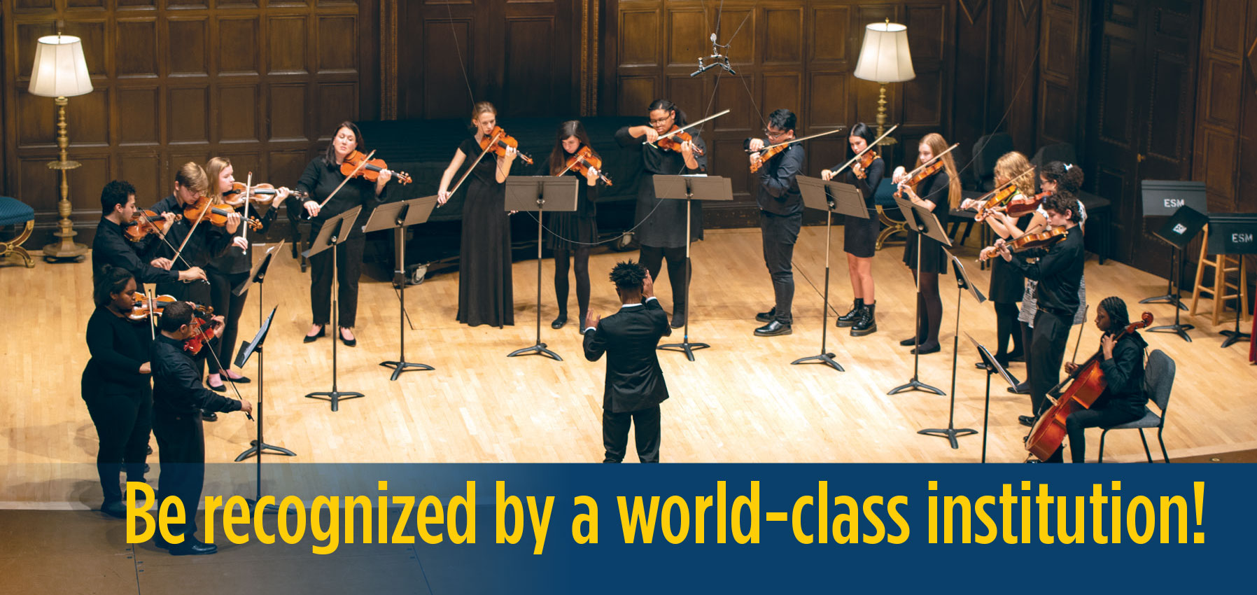 An ECMS Diploma student conducts a string ensemble of his peers on stage in a concert at Kilbourn Hall