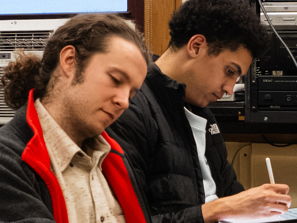 Photo of two students leaning over notebooks and writing