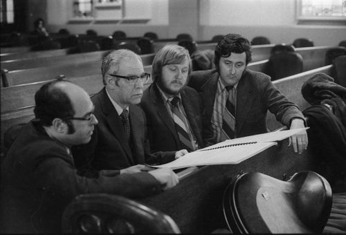 R1308-28 During a rehearsal in Lake Avenue Baptist Church, Eastman School composers Samuel Adler, Wayne Barlow, and Joseph Schwantner peruse the score of the Concerto for Organ and Orchestra, joined (at right) by local music critic Ted Price.