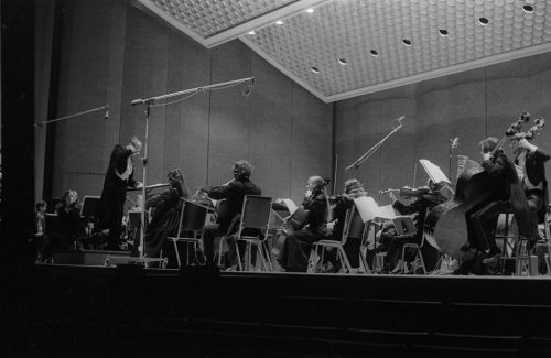 Eastman Philharmonia concert that featured the premiere of Krzystof Penderecki’s Partita for Harpsichord and Orchestra. At the conclusion of the Partita, Maestro Hendl invites the composer to the stage for bows. In the last shot, the composer, the soloist, and the conductor all join hands to acknowledge the applause.