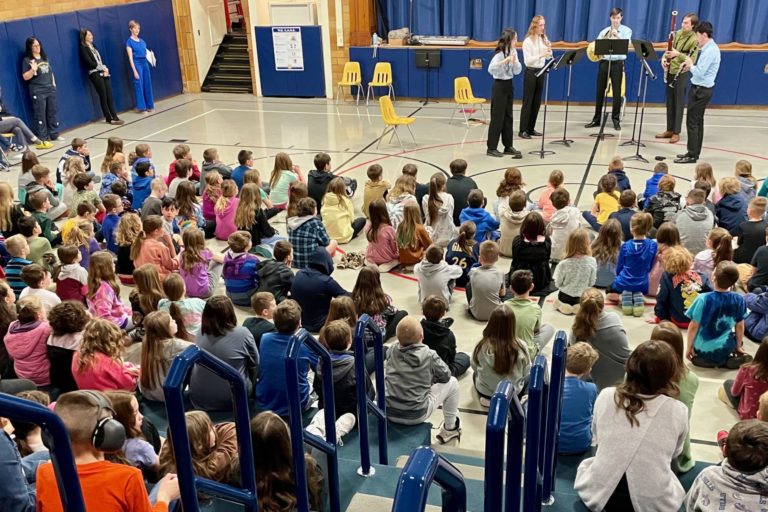Children listening to chamber music group in school gymnasium