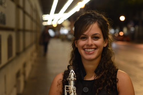 Eastman saxophone student Alexa Tarantino smiling in front of the school at night time.