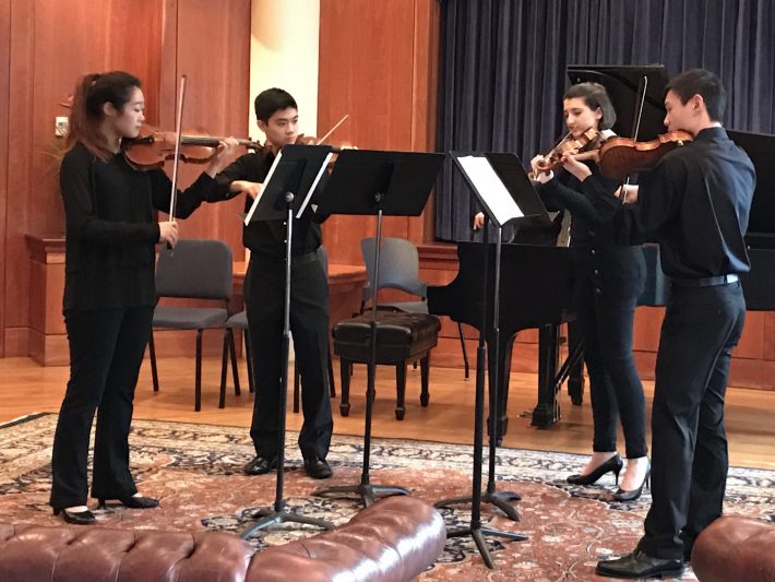 Violinists Hannah Chou, Jonathan Eng, Elizabeth Smith, and Michael Wu perform in Ciminelli Lounge