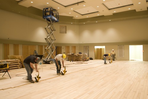 Workers install plywood flooring