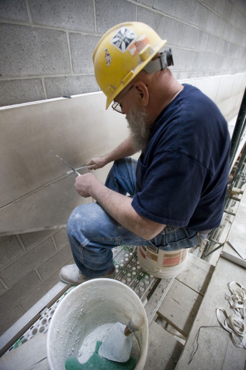 A worker puts limestone on an interior atrium wall