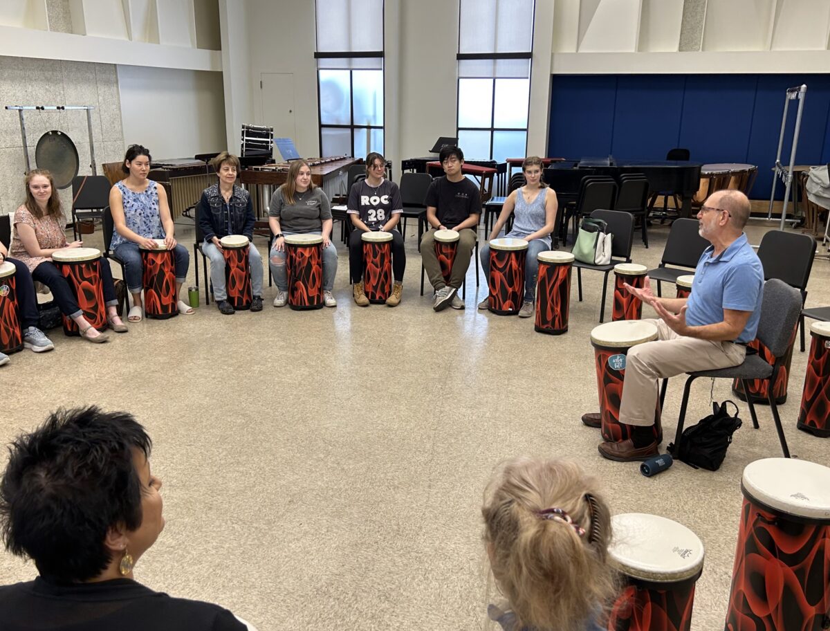 Beck leads a drum circle with students and faculty