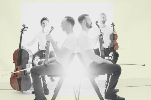 A press kit photo of the JACK Quartet with a bright light in the center.