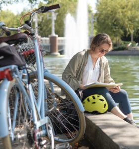 Lisa Bielawa sits beside water, near a parked blue bike